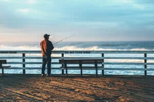 A person enjoying fly fishing on a pier, illustrating the mental health benefits of spending time in nature and engaging in mindful activities. Fly Fishing for Mental Health