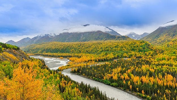 A panoramic view of Alaska's river valleys in autumn, where anglers can find serene fly fishing spots amidst vibrant fall foliage